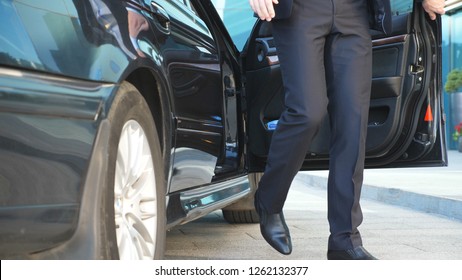 Businessman Opens Door And Get Out From The Car Near Modern Office Building. Young Business Man Uncover Door Of Automobile. Guy In Suit Exit From Black Auto. Commuter To Job. Slow Motion Close Up.