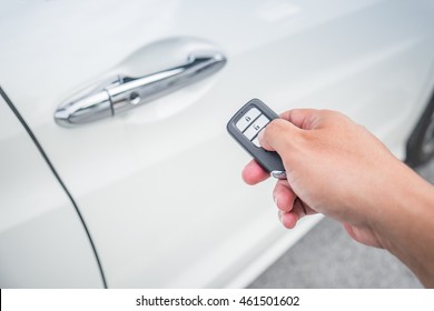 Businessman opens his luxurious car door with a modern remote control key. The young man is locking the automobile with the security system. Keyless in male hand with copy space.
