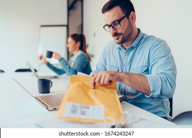 Businessman Opens An Yellow Envelope In Office