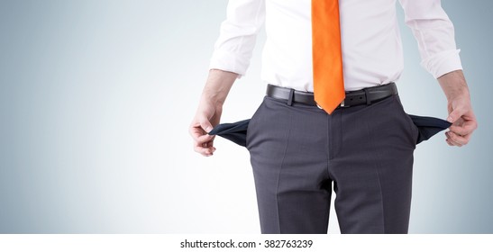 Businessman With An Orange Tie Turning His Empty Pockets Inside Out. Front View, No Head. Grey Background. Concept Of Bankruptcy.