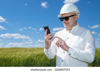 Businessman Outdoors. Business Owner In Protective Helmet. Concept Finding Place For Construction. Site Selection For Building Construction. Man With Phone In Shirt. Businessman In Front Green Field