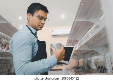 Businessman Owner Staff Using Computer Laptop Checking Product Inventory Shelf In Grocery Store