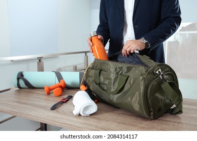 Businessman Packing Sports Stuff For Training Into Bag In Office, Closeup