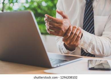 Businessman pain in hands while woking with laptop. Office syndrome concept. - Shutterstock ID 1296208102
