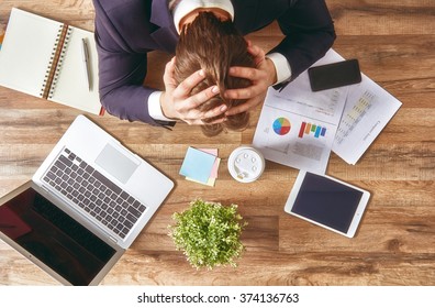 businessman in panic. a young man sits at his Desk and holds his hands on his head. - Shutterstock ID 374136763