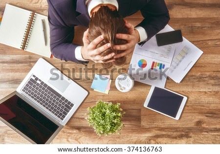 businessman in panic. a young man sits at his Desk and holds his hands on his head.