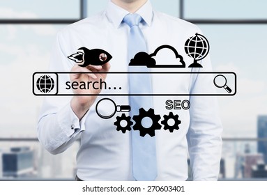 Businessman in a panoramic office is drawing the internet search bar and different icons. A concept of business management process. - Shutterstock ID 270603401