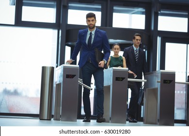 Businessman Passing Through Turnstile Gate At Office