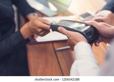 Businessman paying by credit card with a credit card reader machine in a restaurant