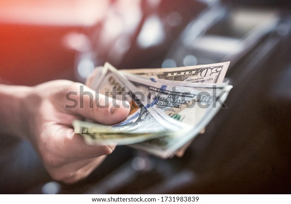 businessman pays for a product or\
service, gives dollars while sitting in the car. finance\
concept