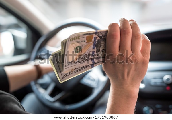businessman pays for a product or\
service, gives dollars while sitting in the car. finance\
concept
