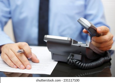 Businessman is picking up the headset for help, while reading legal document - Powered by Shutterstock