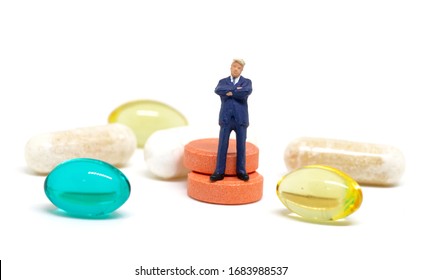 Businessman And Pills On White Background. Miniature Figurine Of Business Man Macro Photo. Pharmacy Corporation And Heathcare Industry. Drug Production Profit. Pharma Business Concept. Medical Control