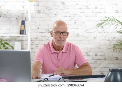 A Businessman With A Pink Polo Shirt Works In His Office