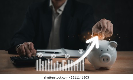 Businessman placing coin into a piggy bank with rising financial chart overlay, savings, investment growth, and financial planning. economic success and wealth accumulation. - Powered by Shutterstock