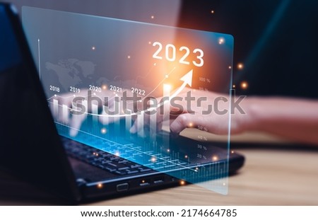 Businessman planning 2023 business growth on desk with virtual hologram chart graph. Calculate income and profit on investments and an increase in the indicators of positive growth, Return on Stocks