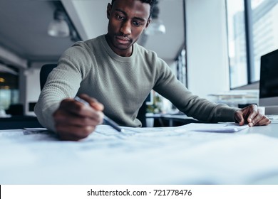 Businessman Pointing At Building Plan In Office. Black Man Working On Construction Plan.