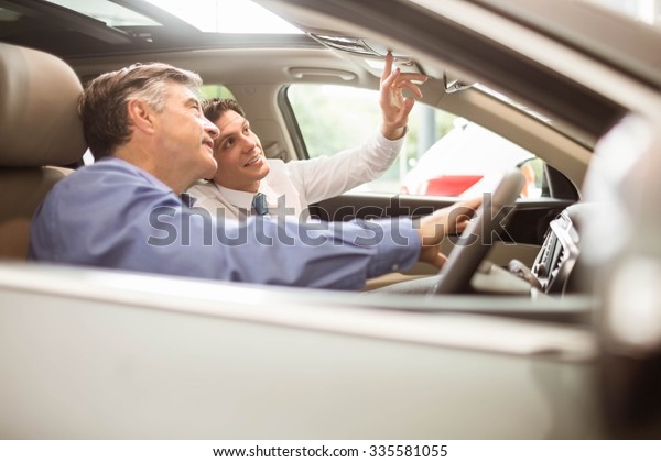 Businessman\
pointing a car interior at new car\
showroom