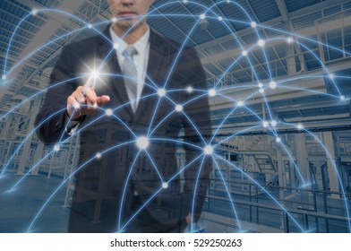 Businessman pointing with digital network line and circles over factory background, business technology concept