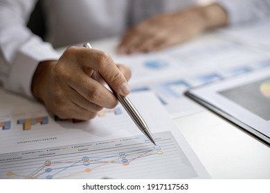 A Businessman Pointing At A Document With A Pen To Check The Financial Numbers, He Is Sitting In His Private Office, The Businessman Examining The Financial Data From The Corporate Finance Chart.