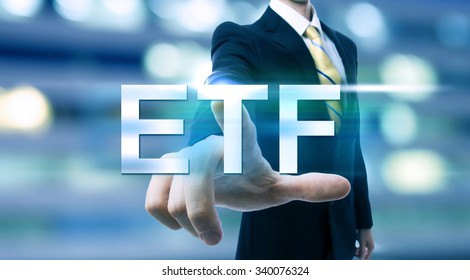 Businessman Pointing At ETF (Exchange Traded Funds) On Blurred City Background