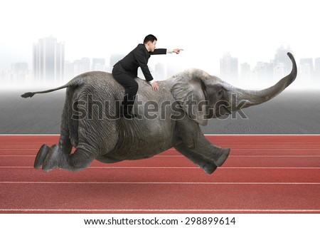 Businessman with pointing finger gesture riding on elephant, with city skyline and red track background.
