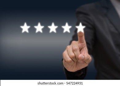 Businessman pointing five star symbol to increase rating of company or hotel on dark tone background, business evaluation concept, Increase rating