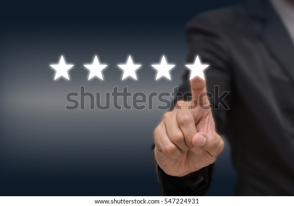 Businessman pointing five star symbol to increase\
rating of company or hotel on dark tone background, business\
evaluation concept, Increase\
rating