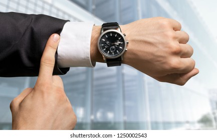 Businessman Pointing At Hand Watch On Grey Wall Background, Close-up