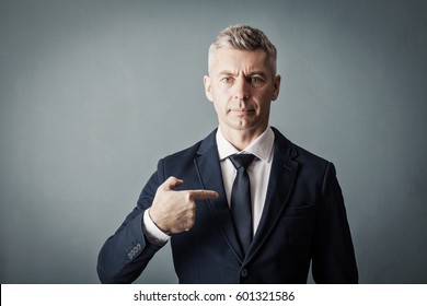 Businessman is pointing at himself on gray background