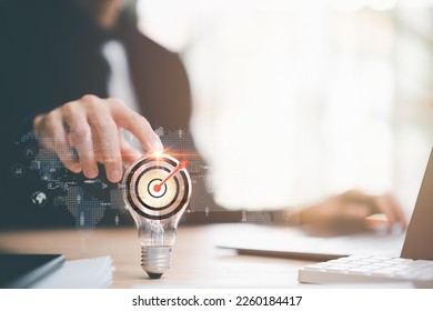 businessman pointing to a light bulb and arrow icon hitting center of dartboard target,Setting business goals and focused concepts, Organizational growth and objectives, marketing strategy planning - Shutterstock ID 2260184417