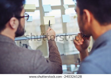 Businessman pointing at notepaper while explaining his idea to colleague