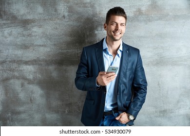 Businessman Portrait. Successful good-looking happy young businessman with mobile phone.