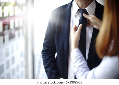 businessman prepare to go to present the project and the assitant help to adjust necktie