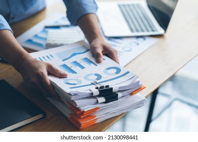 Businessman Preparing reports papers with graphs, charts on Stacks of documents files for finance in office. Piles unfinished achieves with paper clip near computer. Concept of Business Annual Report.