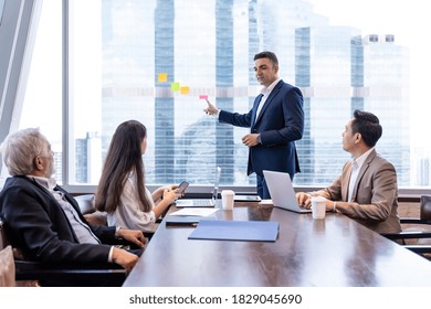 Businessman presenting to colleagues in the meeting room with cityscape blur background. Business team brainstorming ideas about scheme for investment at office. business, people, office concept - Shutterstock ID 1829045690