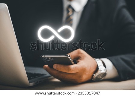 Businessman presents smartphone with infinity symbol, signifying limitless connection in data technology, future unlimited. Infinite power, energy, internet information. technology infinity data