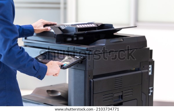Businessman press\
button on panel of printer photocopier  network , Working on\
photocopies in the office concept , printer is office worker tool\
equipment for scanning and copy\
paper.