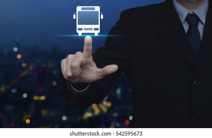 Businessman Pressing Bus Flat Icon Over Blur Colourful Night Light City Tower Background, Business Transportation Service Concept
