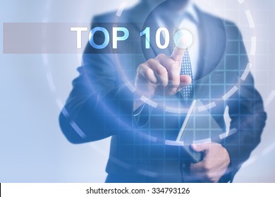 Businessman pressing button on touch screen interface and select Top 10. Business, internet, technology concept.