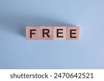 Businessman pressing his finger on the wooden cubes with the word free. Business promotion, free of charge, free trial or delivery concept.