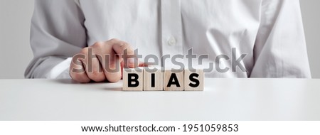 Businessman pressing his finger on the wooden cubes with the word bias. Racial or gender prejudice in workplace concept.