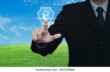 Businessman Pressing House With Shield Flat Icon Over Green Grass Field With Blue Sky, Business Home Insurance And Security Concept