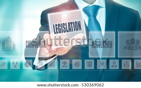 A businessman pressing a Legislation button on a transparent screen.