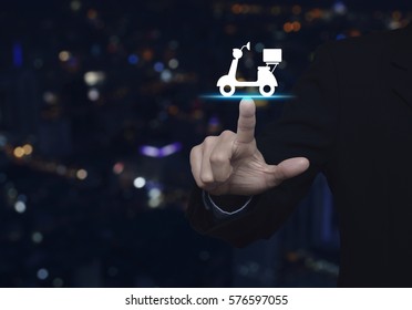 Businessman Pressing Motor Bike Icon Over Blur Colorful Night Light City Tower, Business Delivery Service Concept
