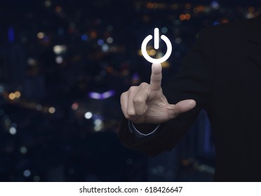 Businessman pressing power button over blur colorful night light city tower, Start up business concept