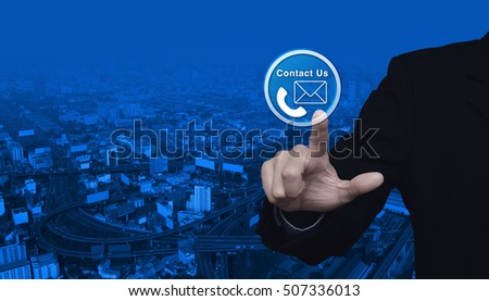 Businessman pressing telephone and mail icon button over city tower and street blue tone background, Contact us concept