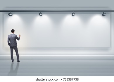 Businessman pressing virtual button on the wall lit with spotlig - Powered by Shutterstock