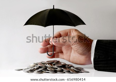 Businessman Protecting Coins With Umbrella. Financial safety Concept.