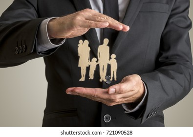 Businessman protecting family silhouette with a father, mother, baby and two children with his cupped hands in conceptual image of life insurance and security. - Powered by Shutterstock